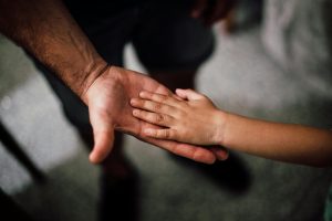 Rhode Island parent and child holding hands, illustrating emotional and legal aspects of child arrears